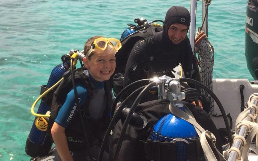 happy child diver and diving instructor on the boat