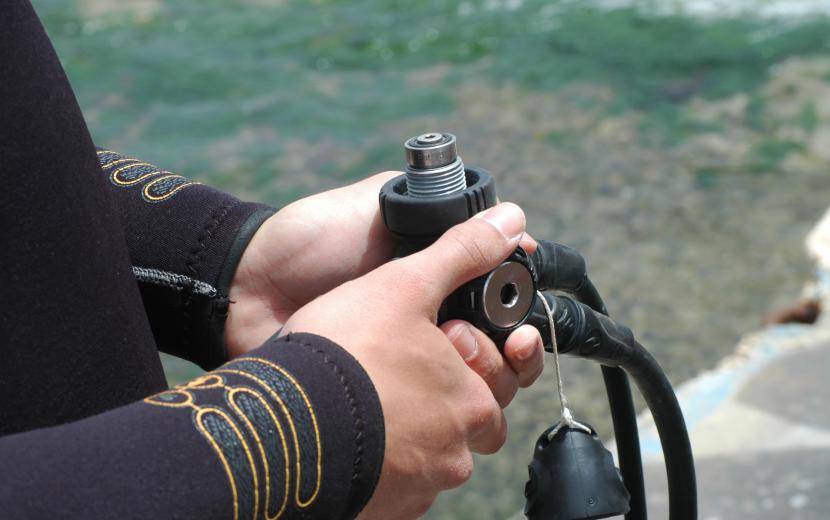 the diver is holding the regulator in his hands